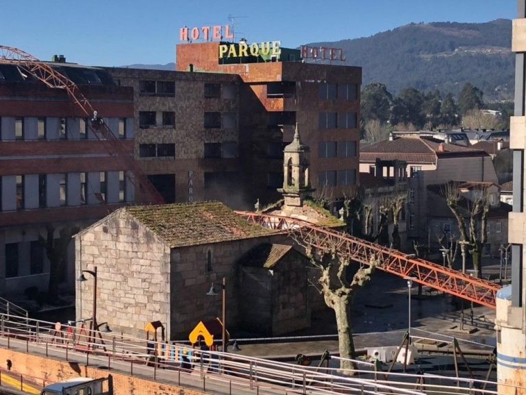 Cae una grúa sobre una capilla y un edificio en O Porriño (Pontevedra), aunque no provoca heridos