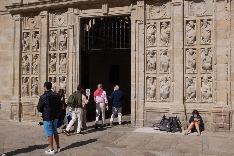 Un hombre escala por las esculturas de la Puerta Santa de la Catedral de Santiago