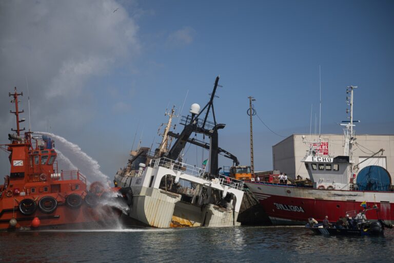 Los bomberos acceden al interior del buque incendiado en Ribeira, mientras prosigue el achique de agua
